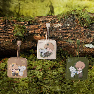 DIMOO ONE DAY WITH KOALA SERIES key case displayed in natural garden setting highlighting the nature-inspired design. Collectible blind box accessory with functional outdoor aesthetic.