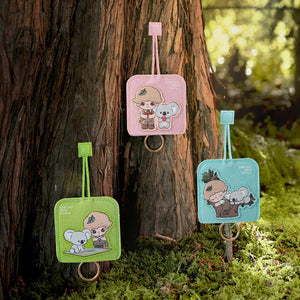 DIMOO ONE DAY WITH KOALA SERIES green key case showcased in natural setting with plant background. Collectible blind box accessory featuring adorable character with functional design.