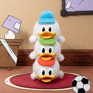 Cute stacked plush figures of Donald Duck's triplet nephews in colorful hats, surrounded by a playful room setting.