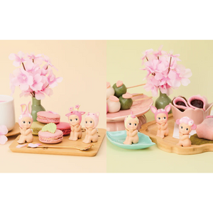 Sonny Angel Cherry Blossom Series figurines among pink treats and flowers, showcasing Hanami Edition charms.