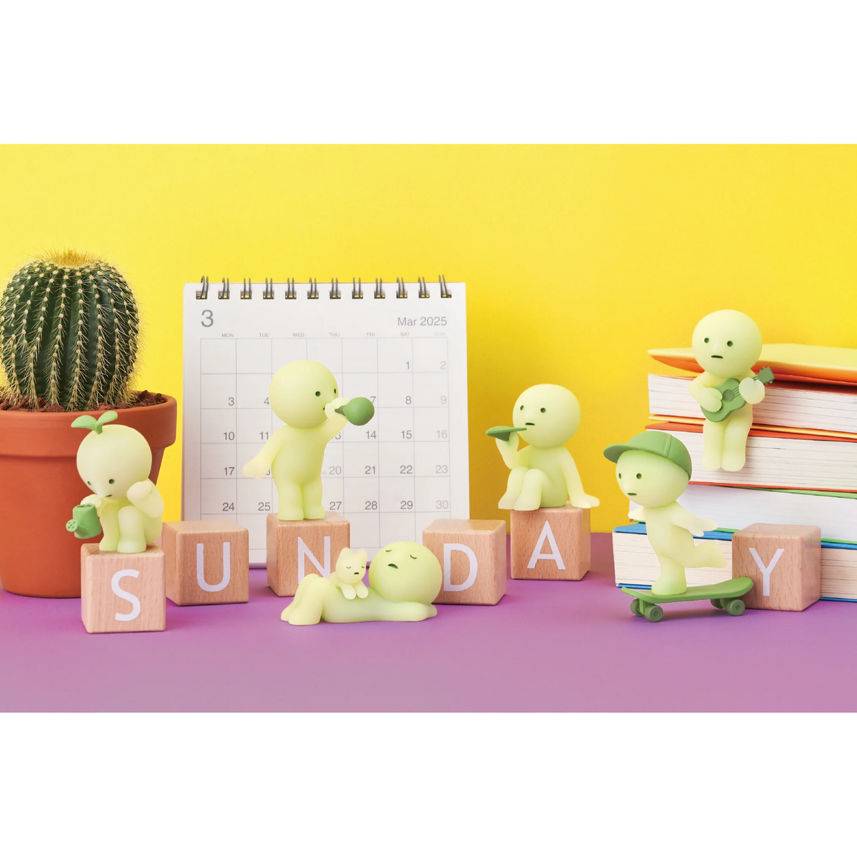 Colorful display of SMISKI figures enjoying Sunday with books, a calendar, and a cactus.