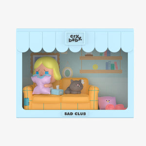 CRYBABY Sad Club Series beach scene set with miniature characters and detailed beach accessories. Collectible diorama featuring emotional storytelling elements against blue background.