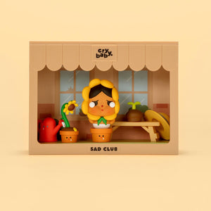 CRYBABY Sad Club Series kitchen diorama with warm yellow background featuring detailed miniature appliances and emotional character. Collectible scene set with domestic storytelling theme.